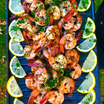 Platter of marinated grilled shrimp, garnished with lemon slices, set on a buffet at a dinner party.