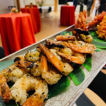 Grilled shrimp appetizer served on a silver tray, with high top tables in the background.
