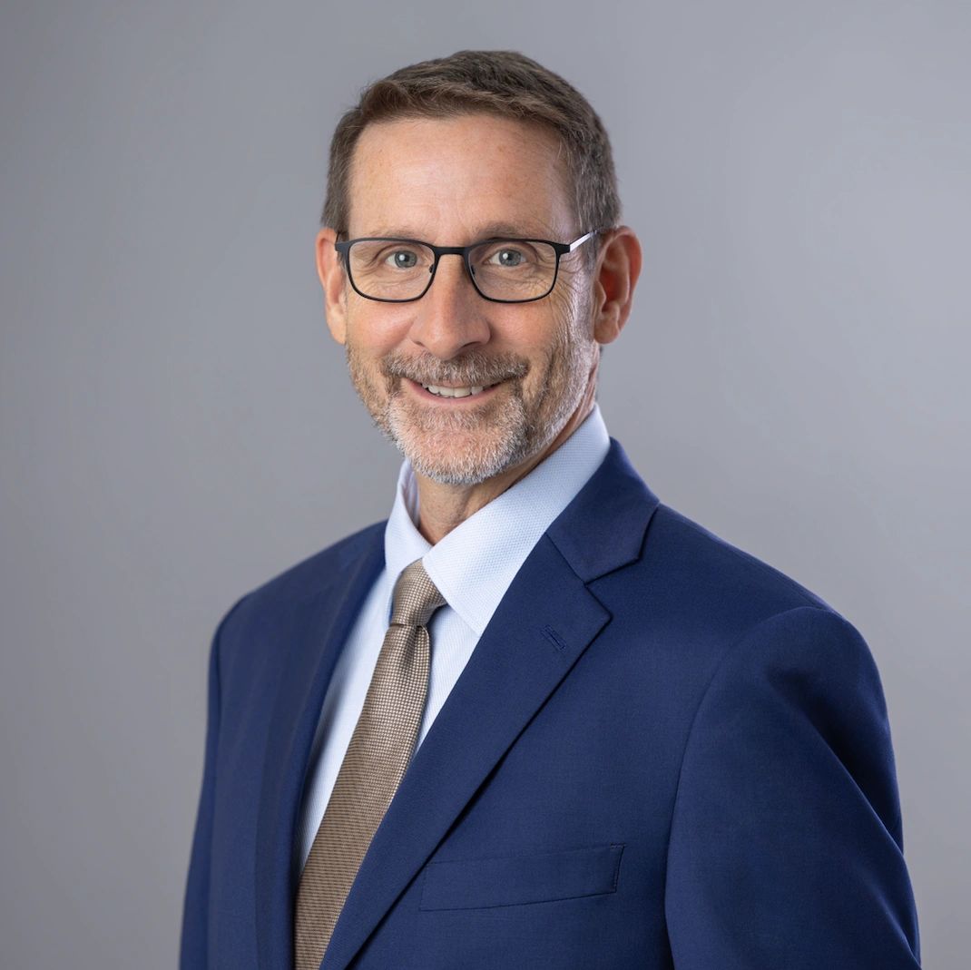 Smiling man in glasses and suit.