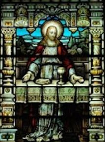 Stained glass window depicting Jesus with a chalice and bread.