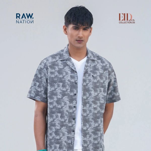 Man wearing a grey patterned shirt and white pants.