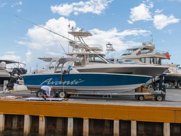 Two men working on a blue boat named Avanti at a dockyard.