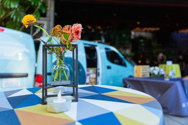highboy table with metal frame vase centerpiece, cement votive and refillery in background