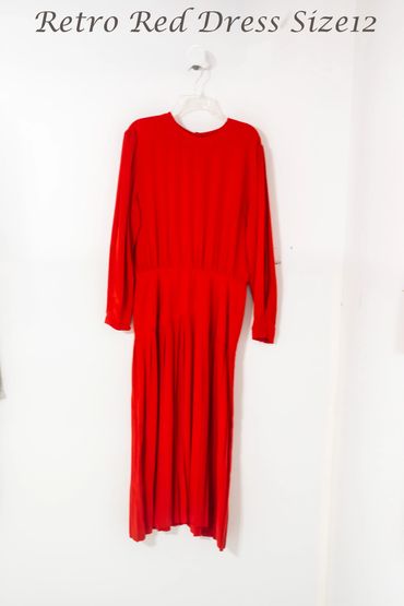 Retro red long-sleeve dress size 12 hanging on a white wall.