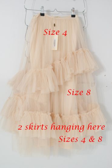 Two delicate beige skirts in sizes 4 and 8 hanging on a rack.
