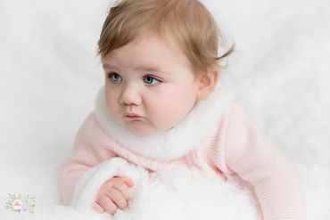 6 month old baby girl posing for her milestone photos , dressed a beautiful pink dress