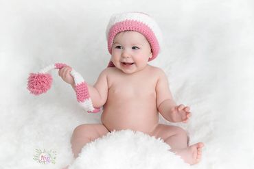 6 month old baby girl posing for her Milestone photo session wearing a cute pink and white cap