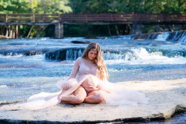 Maternity image of a young mom to be sitting on a rock taking photos at Hurricane Shoals Park