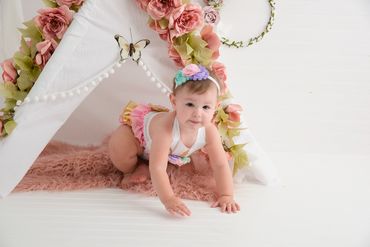 One year old posing for her cake smash session playing at the tee pee