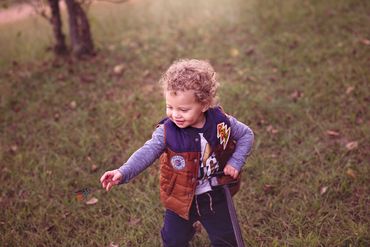 Toddler boy standing outside at the park posing for his photo shoot