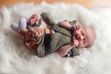 In Home Newborn baby girl laying on a soft cuddly white blanket