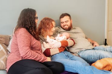 at home newborn session with baby girl, mommy , daddy and big sister sitting in the livingroom
