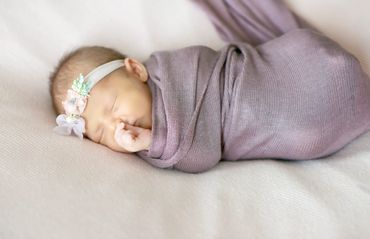 In home newborn session, wrapped in lavendar wrap and floral headpiece