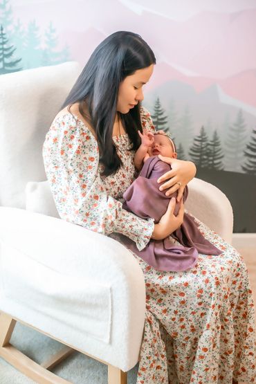 A mother lovingly holds her newborn baby wrapped in a purple blanket.