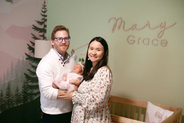 In Home Newborn session with Mom and dad in babies new room , next to her crib