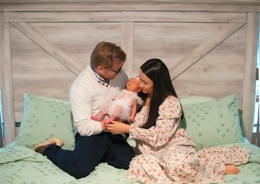 In Home newborn session with Dad and Mom holding baby sitting on their bed