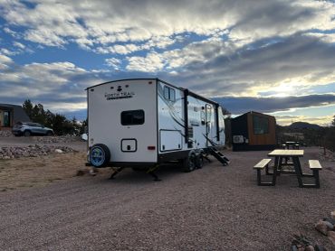 RV parked near a picnic table under a cloudy sky.