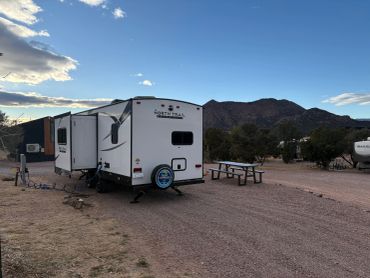 RV parked at a campsite with mountains in the background.