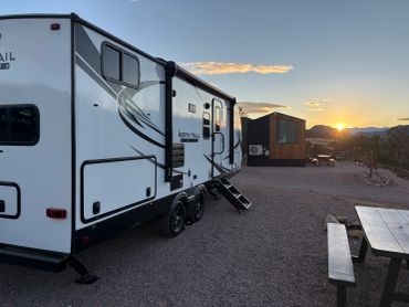 Camper trailer parked at sunset in a quiet campsite.
