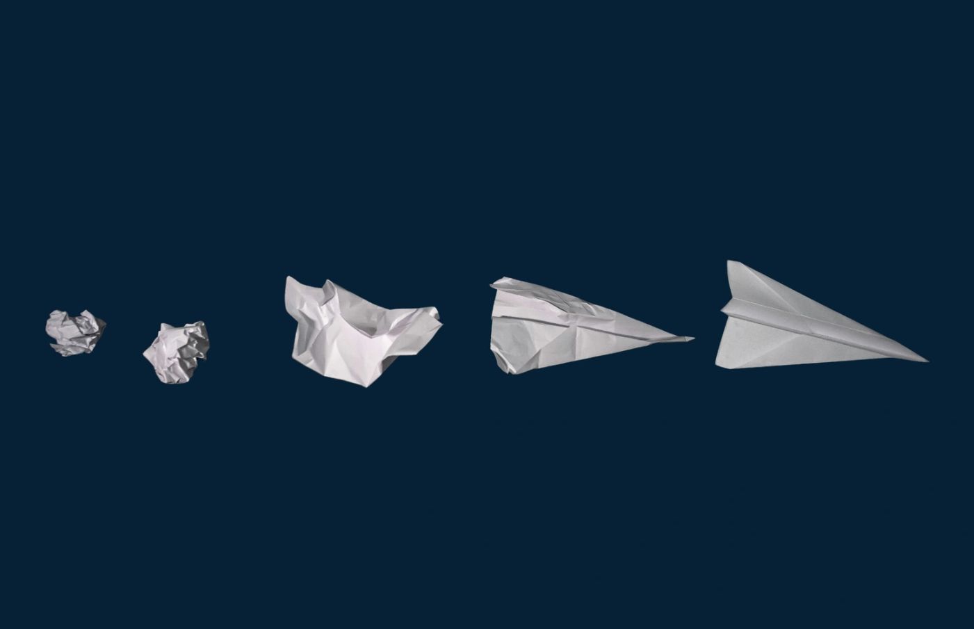 Sequence of paper crumpling transforming into a paper airplane.