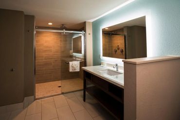 Modern bathroom with glass shower and illuminated mirror.