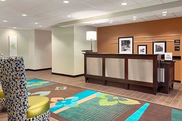 Modern hotel reception area with colorful carpet and framed photos.