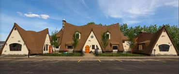 A whimsical house with a brown roof and cream walls under a blue sky.
