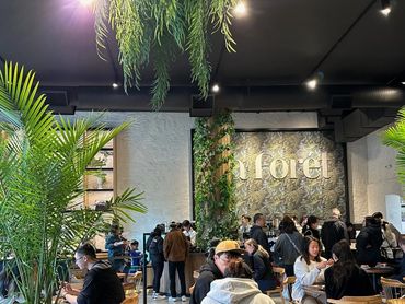 People enjoy a cozy café with lush greenery and warm lighting.