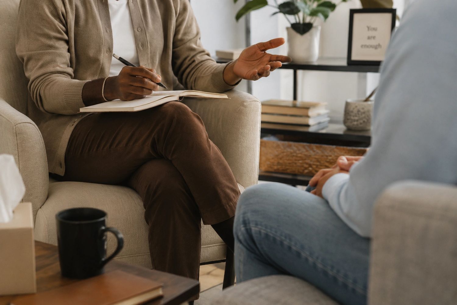 A therapist listens attentively while taking notes during a counseling session.