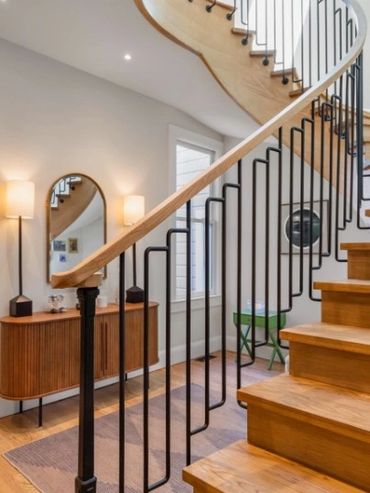 Modern wooden staircase with black metal railing in a stylish hallway.