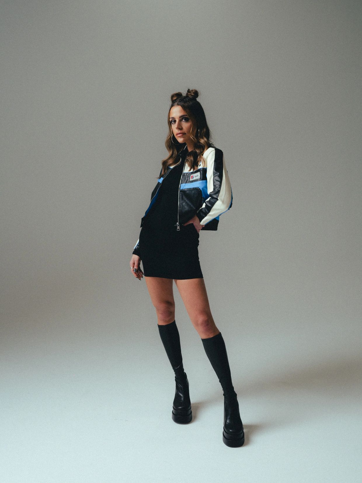 Young woman posing in a black dress and leather jacket.