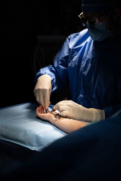Surgeon performing hand surgery under focused light in an operating room.