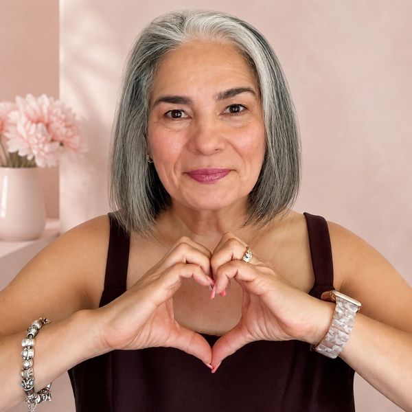 Smiling woman making a heart with her hands.