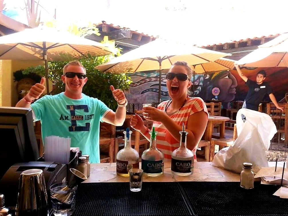 man and woman taking shots of Tequila in Mexico giving a thumbs-up sign