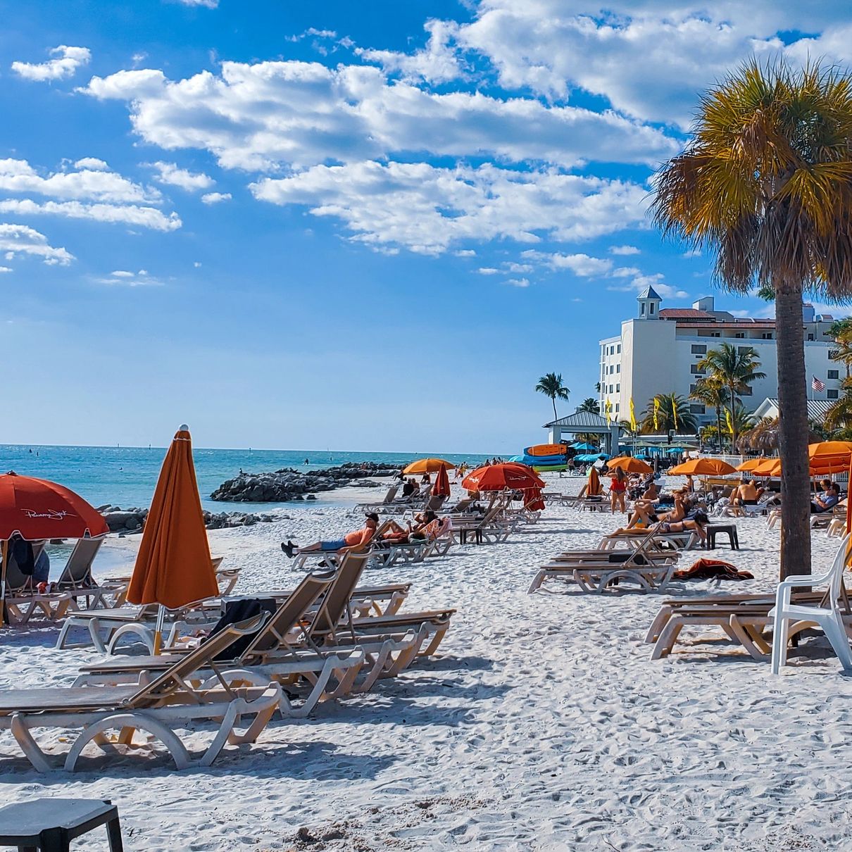 clearwater beach in florida with beach chairs, orange umbrellas and palm trees 
