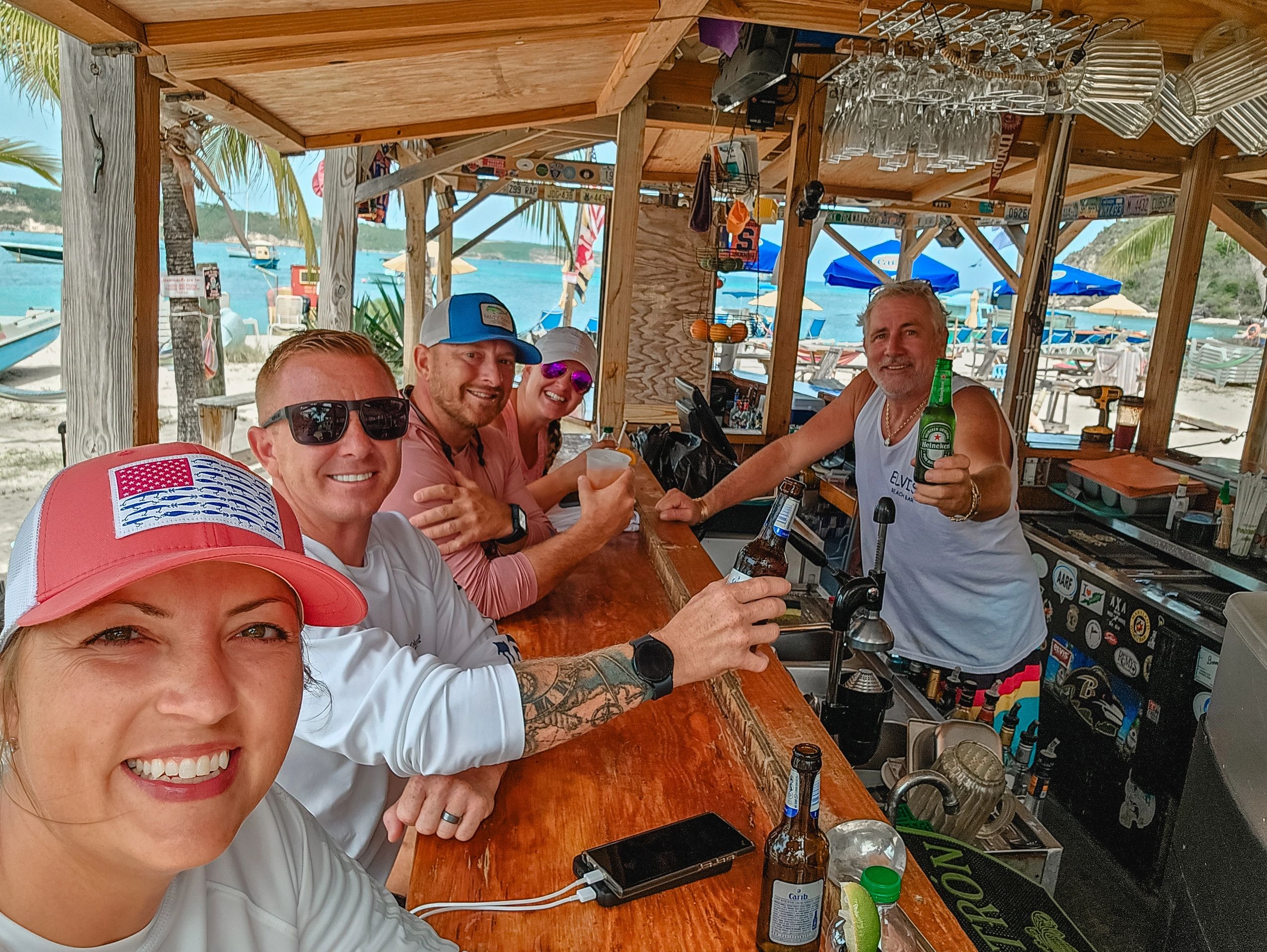 group of people cheersing a beer in Anguilla at Elvis' Beach Bar on Sandy Ground