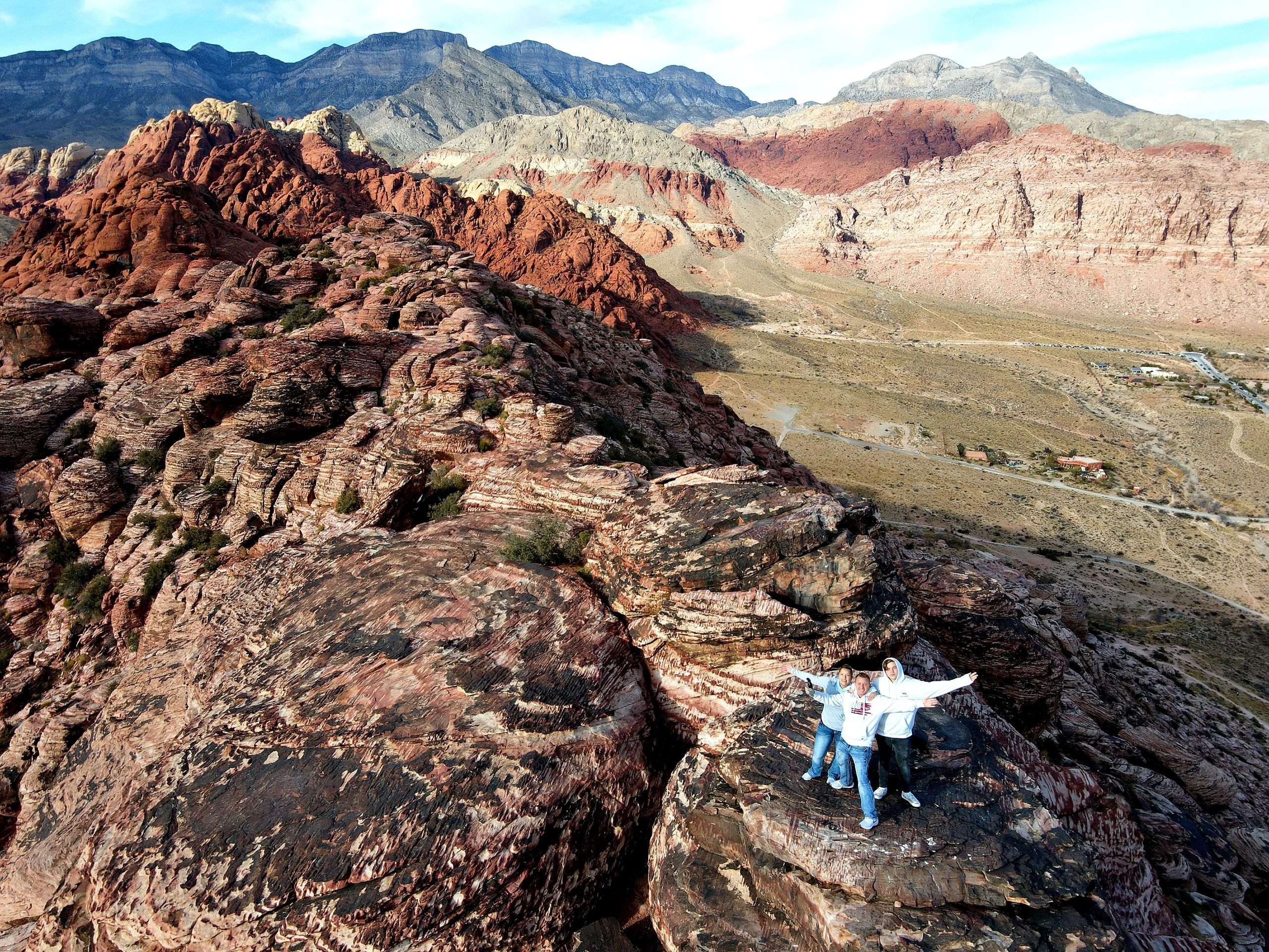 three people standing on top of the red rock canyon sand stone in las vegas