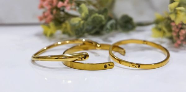 Three elegant gold rings on a white surface with floral background.