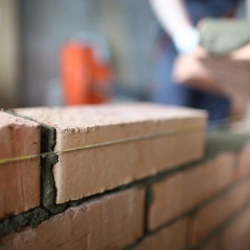 Close-up of bricklayer building a brick wall with mortar.