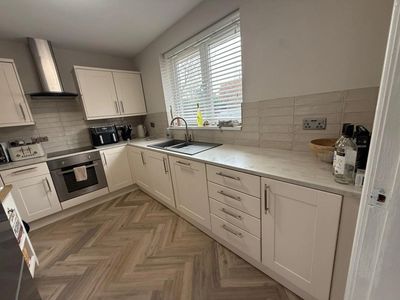 Modern kitchen with white cabinets and herringbone floor.