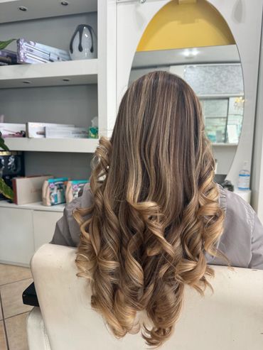 Blonde hair with loose curls styled at a salon.