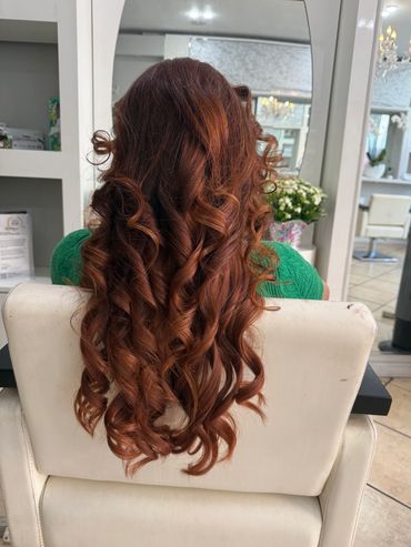 Woman with long, curly reddish-brown hair in a salon.