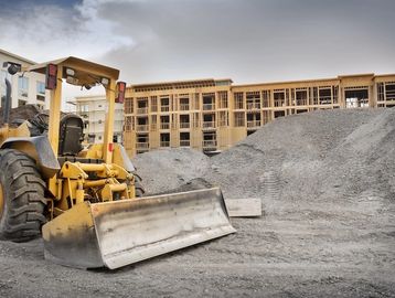 Bulldozer at a construction site with gravel piles and building framework.