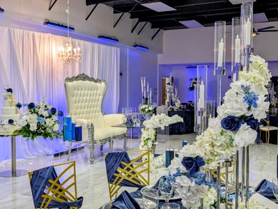 Elegant event setup with white and blue floral decorations and a regal chair.