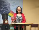 A smiling lady holding a book with a Finally A Broker