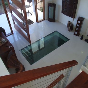 Modern entryway with glass floor panel and wooden accents.