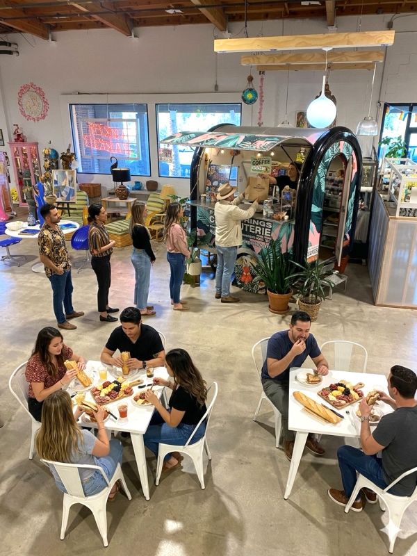 People ordering and eating sandwiches inside a modern indoor food kiosk.