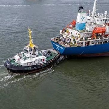 Tugboat assisting a large ship on water.