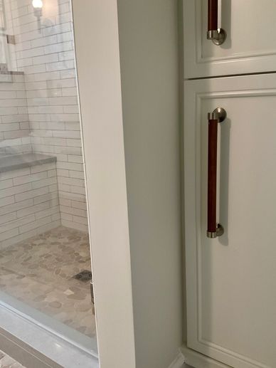 Pebble flooring and custom shower with subway tile and linen closet with leather handles on doors