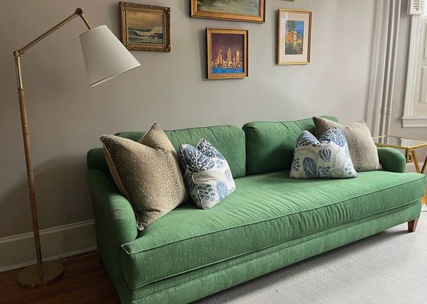 Green sofa with roll arms and rattan floor lamp